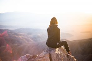woman sitting on cliff looking at horizon